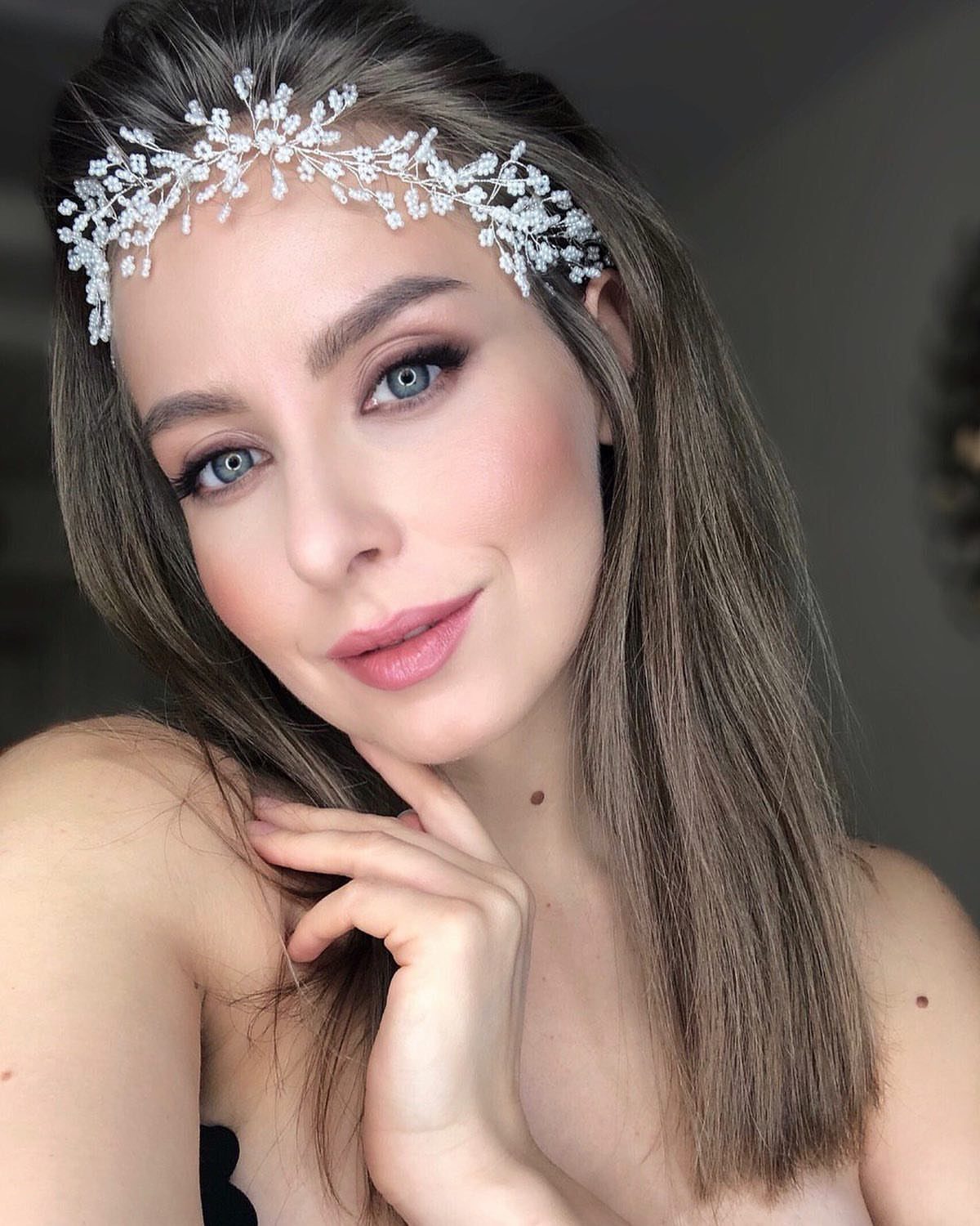 A woman wearing a silver wire vine hairpiece with pearls and crystals across her forehead.